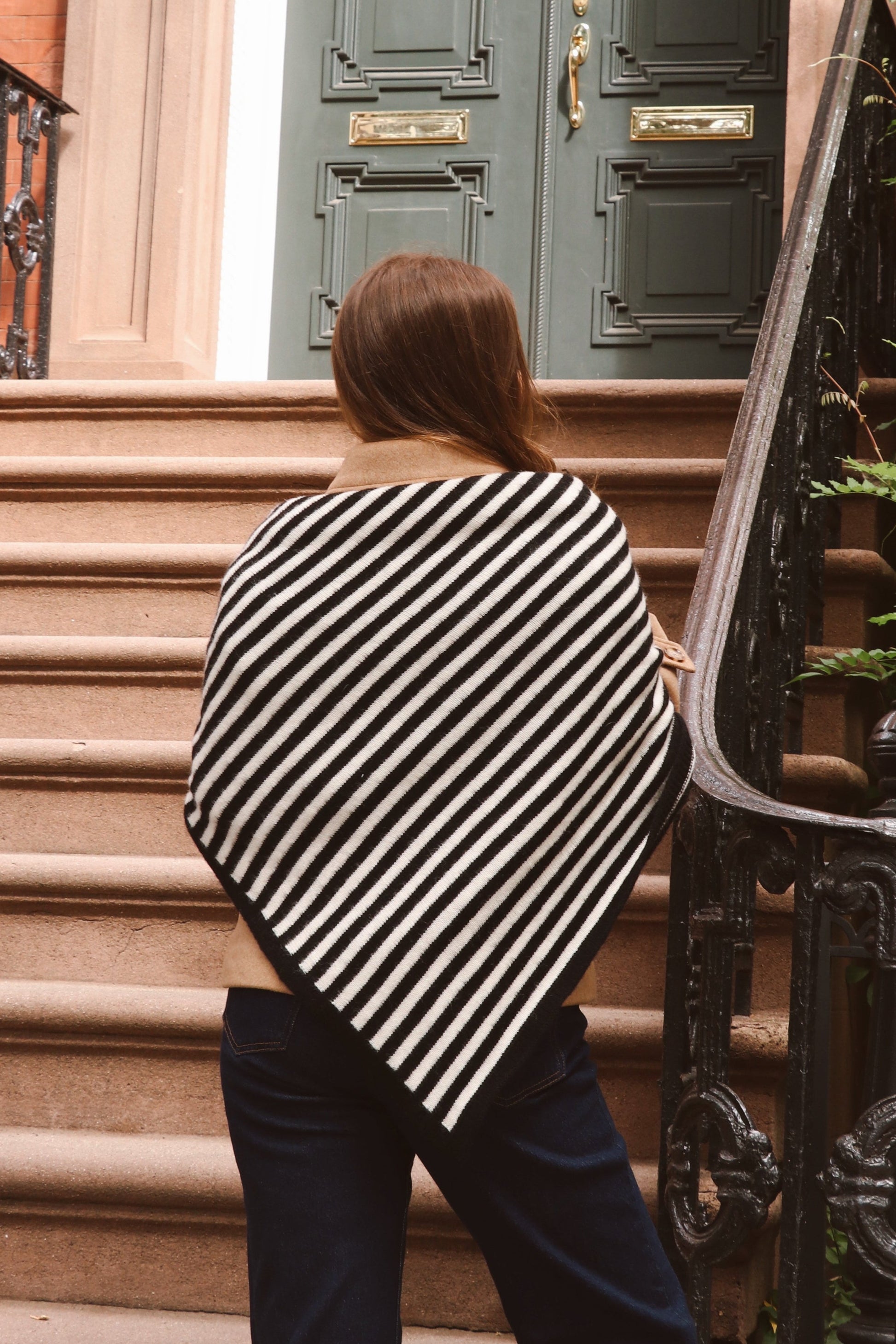 Women wearing a black and white striped shawl standing on a set of stairs.