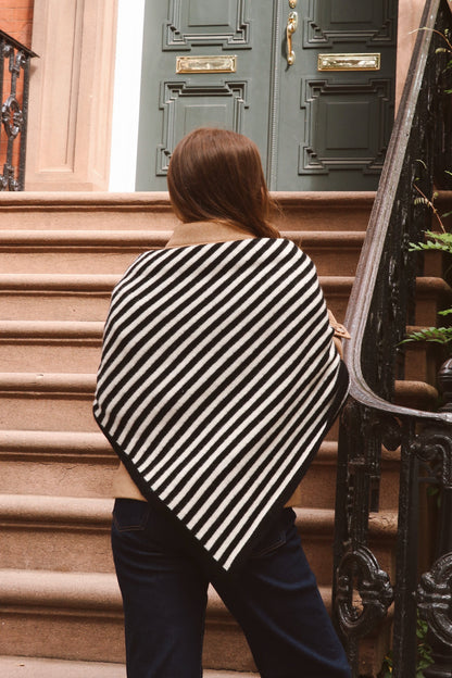 Women wearing a black and white striped shawl standing on a set of stairs.