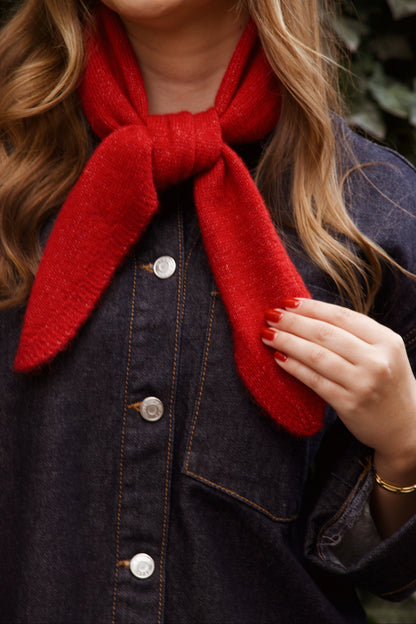 Person wearing a red scarf and dark denim jacket with a blurred background